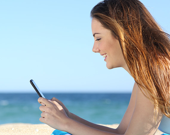 Frau am Strand mit Handy